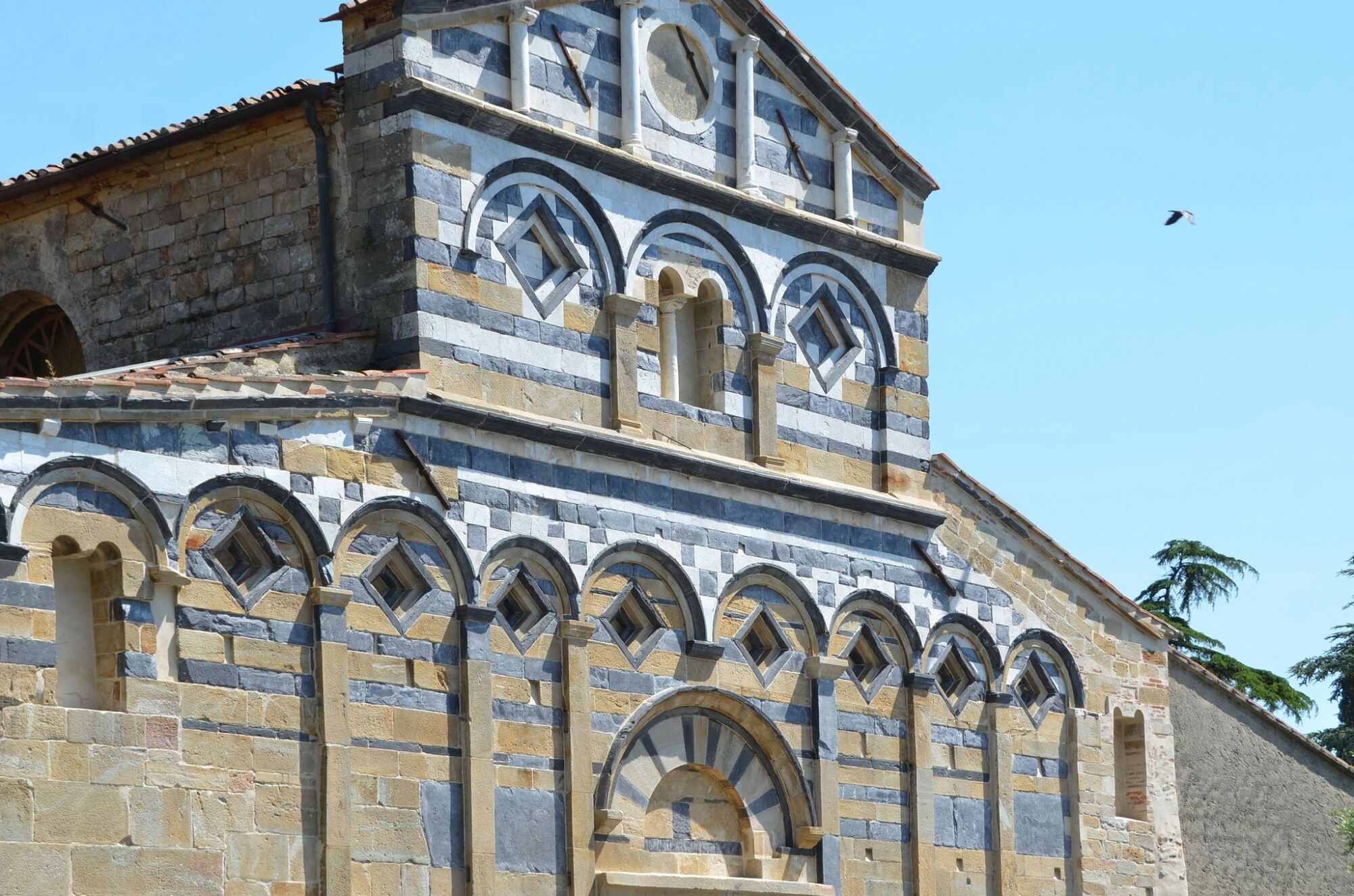 Ein historisches Gebäude mit einer Stein-Fassade, zahlreichen Rundbogenfenstern und einem Glockenturm.