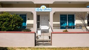Un bâtiment avec une enseigne indiquant « Lucky Studios » au-dessus de l’entrée. Il y a deux fenêtres au rez-de-chaussée, une porte et un petit balcon avec une balustrade.