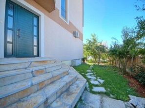 entrance leads to a well-maintained home surrounded by a neatly trimmed lawn and secure fence.