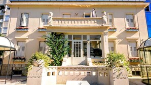 Ein Gebäude mit einem zentralen Eingang, dekorativen Säulen und Blumenkästen.