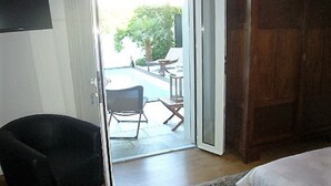 Een hotelkamer met een schuifdeur naar een buitenruimte met een zwembad en meubilair.