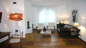 Een woonkamer met een bank, stoelen, een salontafel en een vloerlamp.