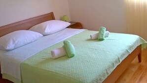 A single bed with a wooden headboard, two white pillows, and a green bedspread. - Apartments Nedjeljka, (15278), Zadar, hr (Zadar)