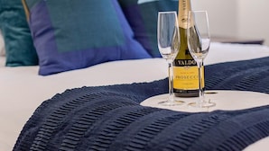 A bed with a bottle of Valdo Prosecco and two glasses on a tray, pillows, and a wall-mounted lamp. - Spacious 3 bed Kensington apartment with Patio (London)