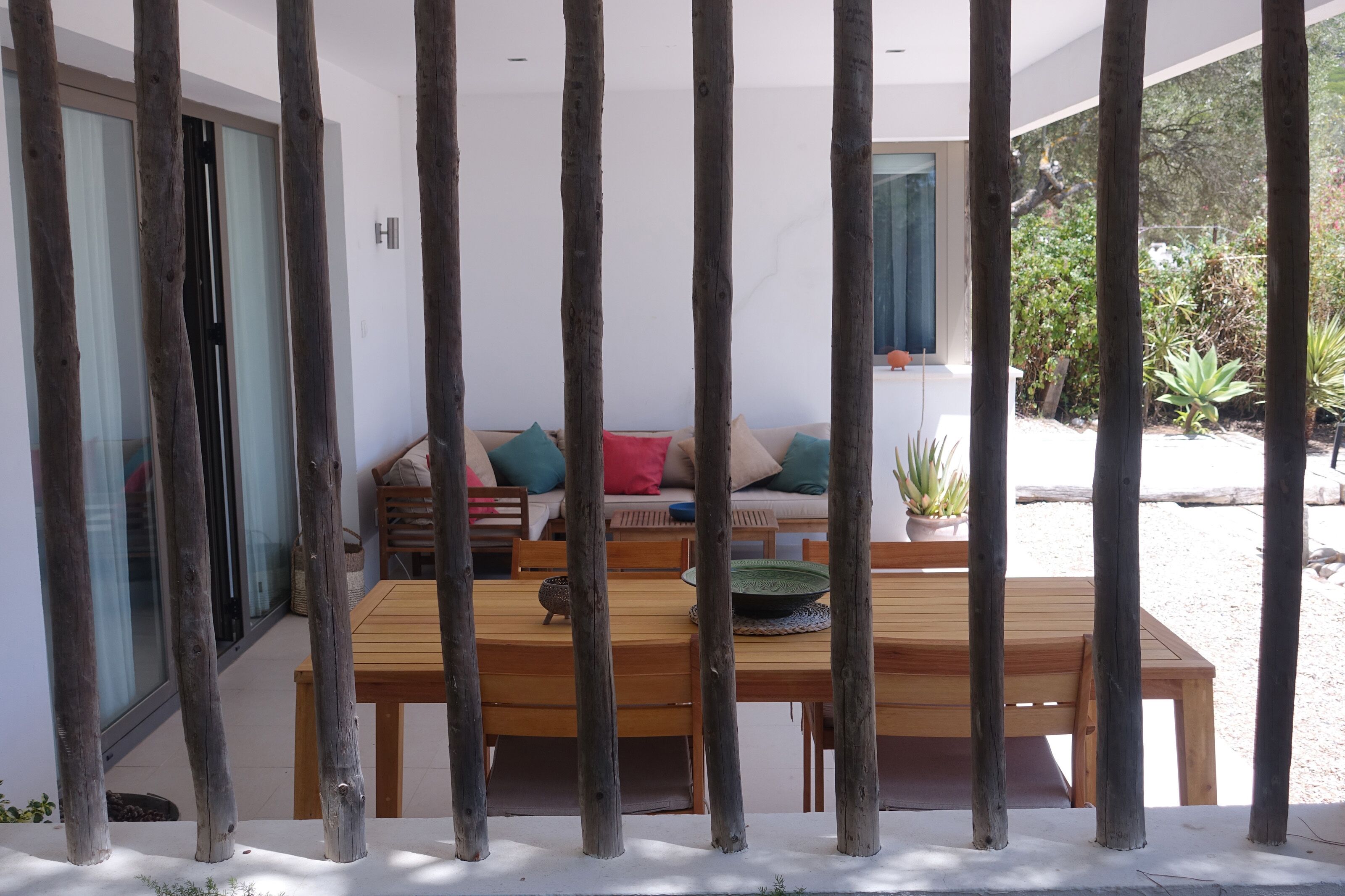 A wooden dining table with chairs, a sofa with cushions, and a sliding glass door in a modern interior.