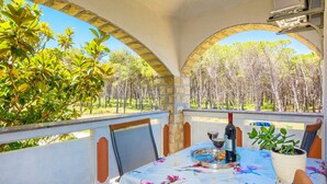 Une terrasse avec une table dressée pour deux personnes, une bouteille de vin et une plante en pot.
