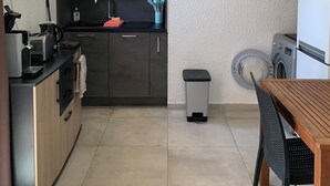Een kleine keuken met een magnetron, broodrooster, spoelbak en een klein afvalbakje.