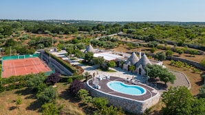 A resort with a tennis court, a swimming pool, and stone buildings with conical roofs. - Luxury trullo, Private  Pool, Air con, Private Tennis Court, Pizza Oven (castellana grotte)