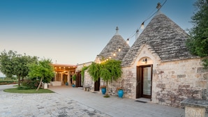 A stone building with conical roofs and a paved walkway. - Luxury trullo, Private  Pool, Air con, Private Tennis Court, Pizza Oven (castellana grotte)