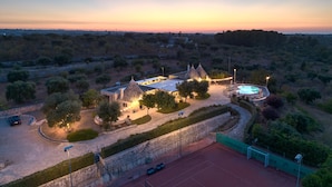 A villa with a swimming pool, surrounded by trees and a stone wall. - Luxury trullo, Private  Pool, Air con, Private Tennis Court, Pizza Oven (castellana grotte)