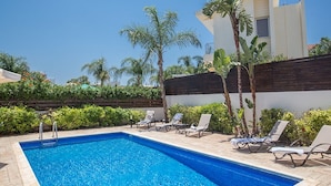 A swimming pool with lounge chairs and palm trees. - Villa Merly, Modern 3BDR Protaras Villa with Pool, Close to Fig Tree Bay Beach (5295)