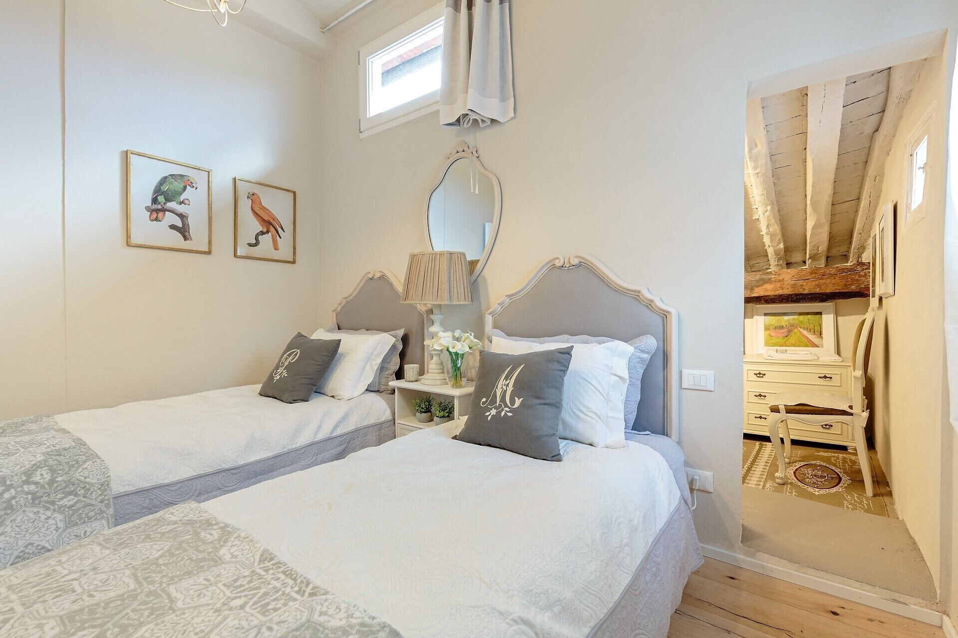 A bedroom with two beds, a mirror, and a window.