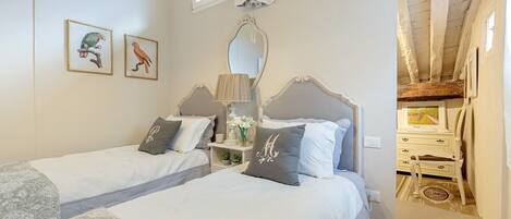 A bedroom with two beds, a mirror, and a window.
