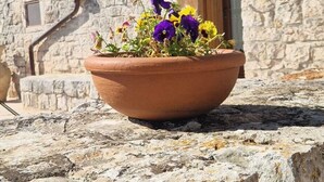 Um edifício de pedra com uma pequena porta em arco e um vaso de flores sobre um parapeito de pedra.