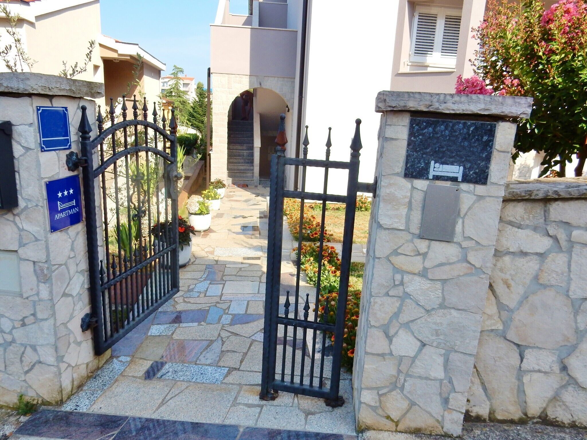 Portão de pedra que dá entrada a um edifício com uma placa azul indicando um apartamento.