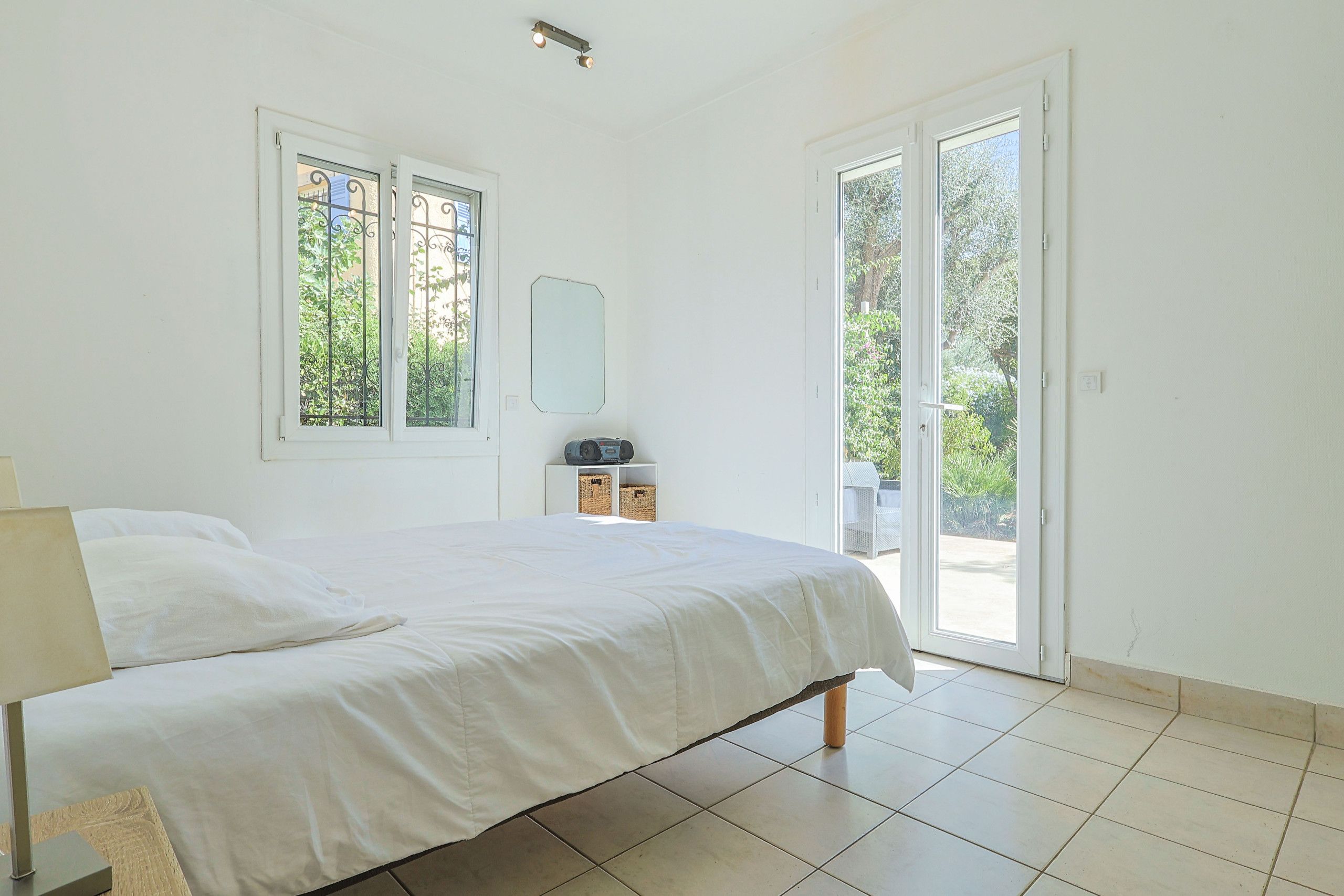 Una camera da letto con un letto, un comodino, una radio e vista sull'esterno tramite una porta.