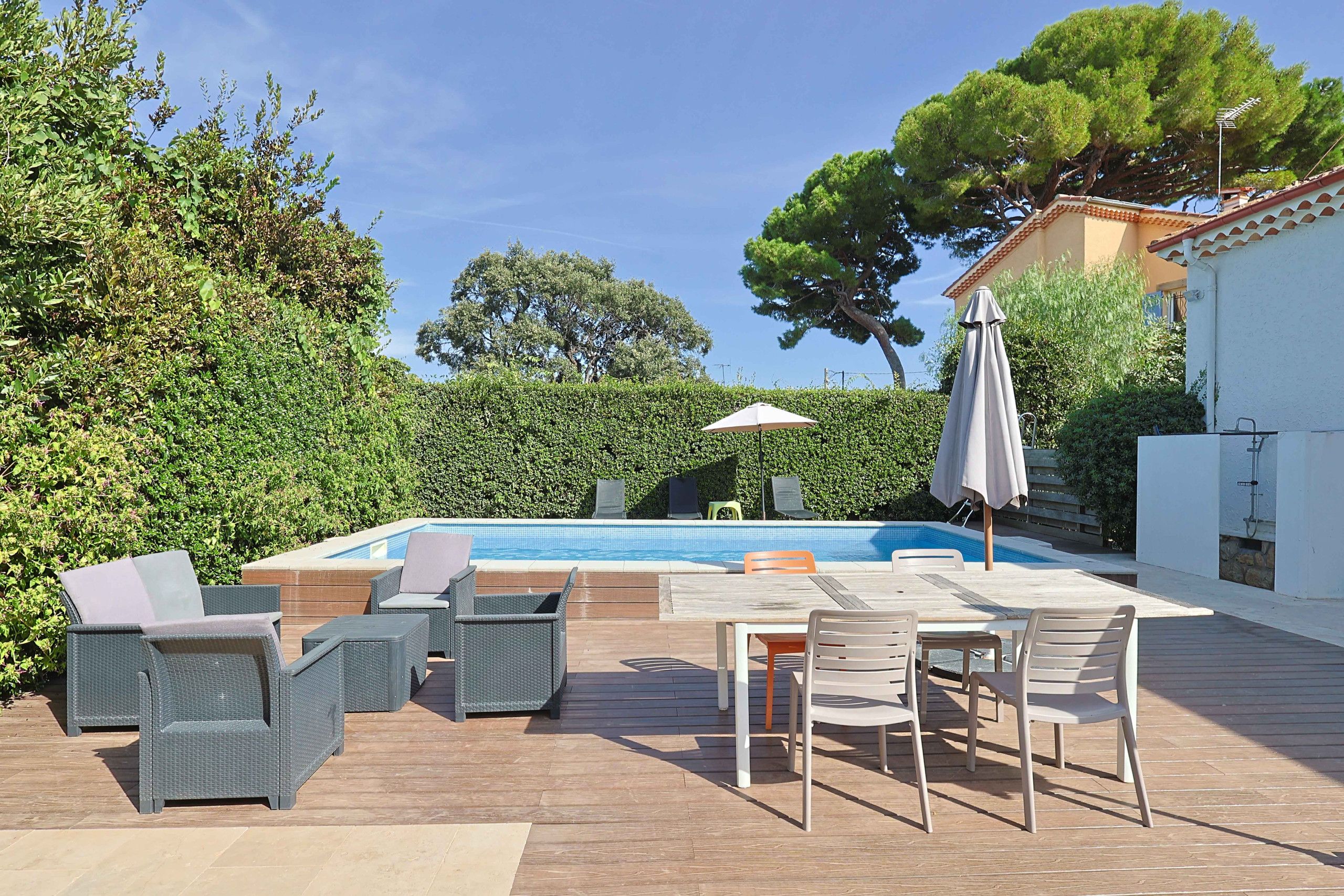 Un espace aménagé au bord de la piscine, avec des chaises longues, une table et des parasols.