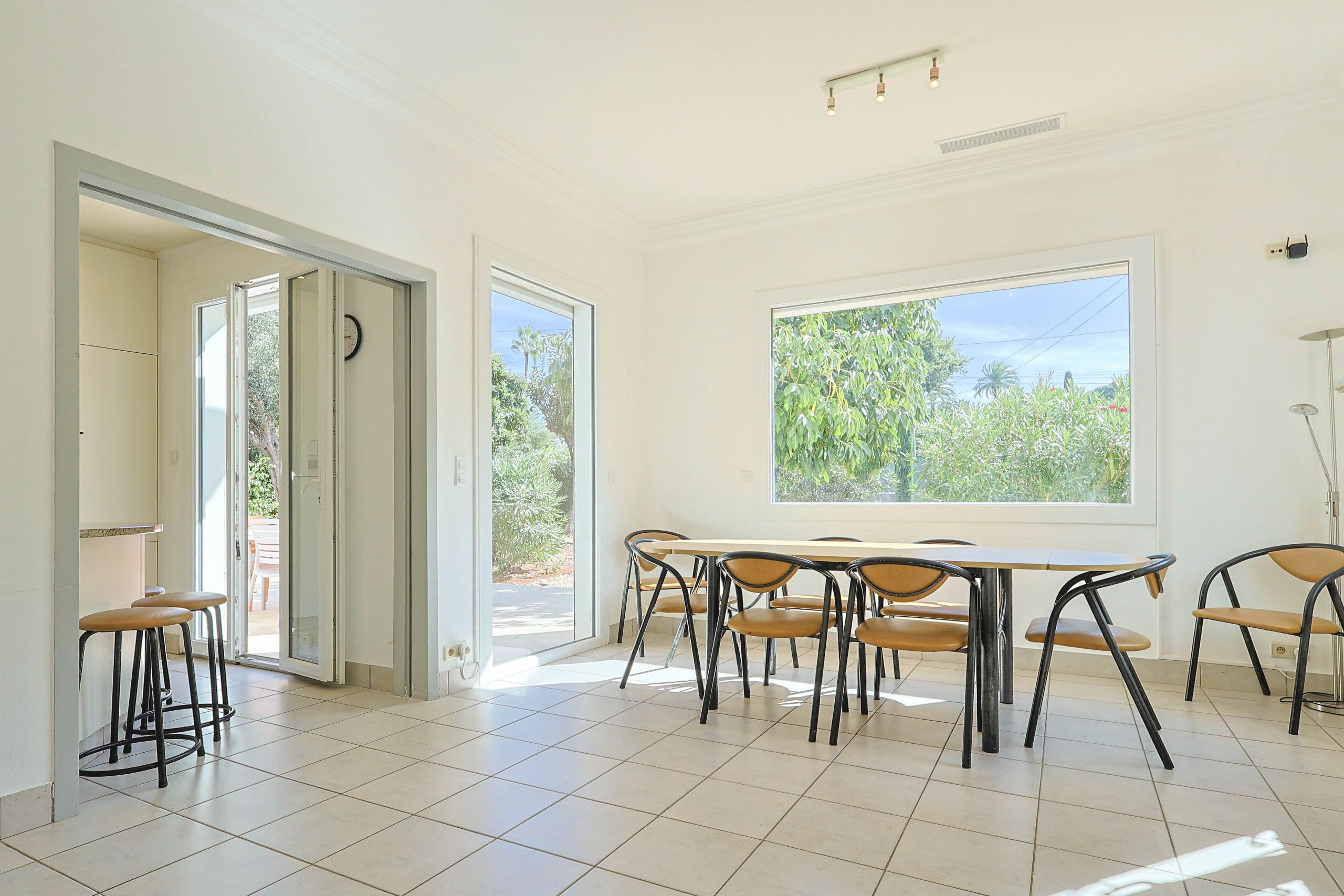 A bright room with a large window, a dining table with chairs, and a door leading outside.