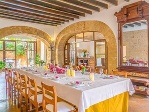 Una larga mesa de comedor dispuesta para una comida, con sillas, una araña y un espejo grande.