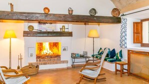 A cozy living room with a fireplace, wooden beams, and comfortable seating.