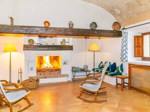 A cozy living room with a fireplace, wooden beams, and comfortable seating.