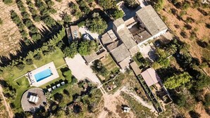 An aerial view of a residential area with a swimming pool, multiple houses, and surrounding vegetation.