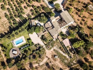An aerial view of a residential area with a swimming pool, multiple houses, and surrounding vegetation.