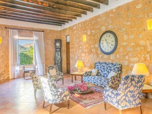 Una habitación con pared de piedra, un reloj grande y un conjunto de sofás.