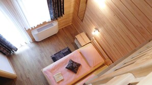 Un interior de madera con una cama, un calentador y una ventana con cortinas.