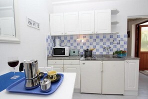 Kitchen area with microwave, toaster, and teapot, adjacent to an entryway.