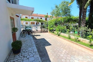 Stroll through the serene courtyard, lined with lush greenery and potted plants, to the entrance of this charming building.
