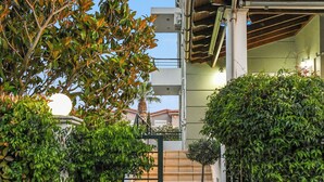 A modern house with a covered entrance, a staircase, and a garden area with potted plants.
