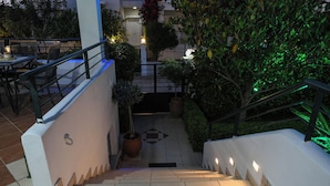 A staircase leading to a rooftop terrace with outdoor seating and potted plants.