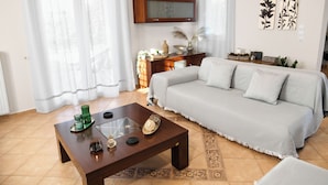A living room with a sofa, coffee table, and a television on a wooden cabinet.