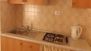 A kitchen with wooden cabinets, a gas stove, a sink, and a kettle. - Apartments Jela, (13827), Makarska, hr (Makarska)