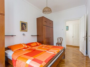 A bedroom with a bed, wooden wardrobe, and a chair.