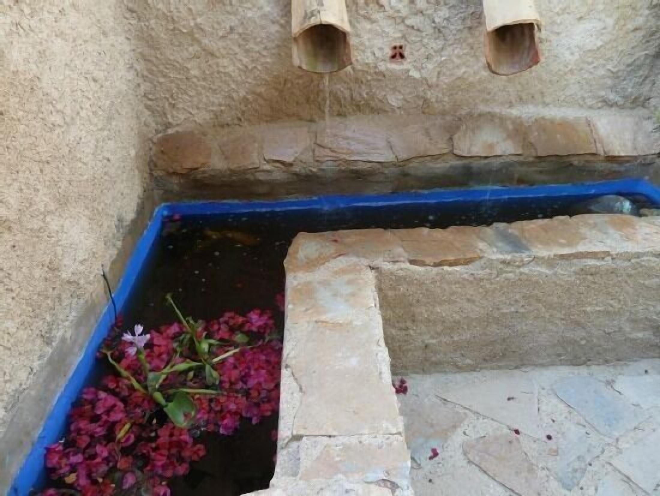 A stone wall with a blue water feature and a flower arrangement.