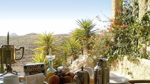 A table set for breakfast with a view of a desert landscape.