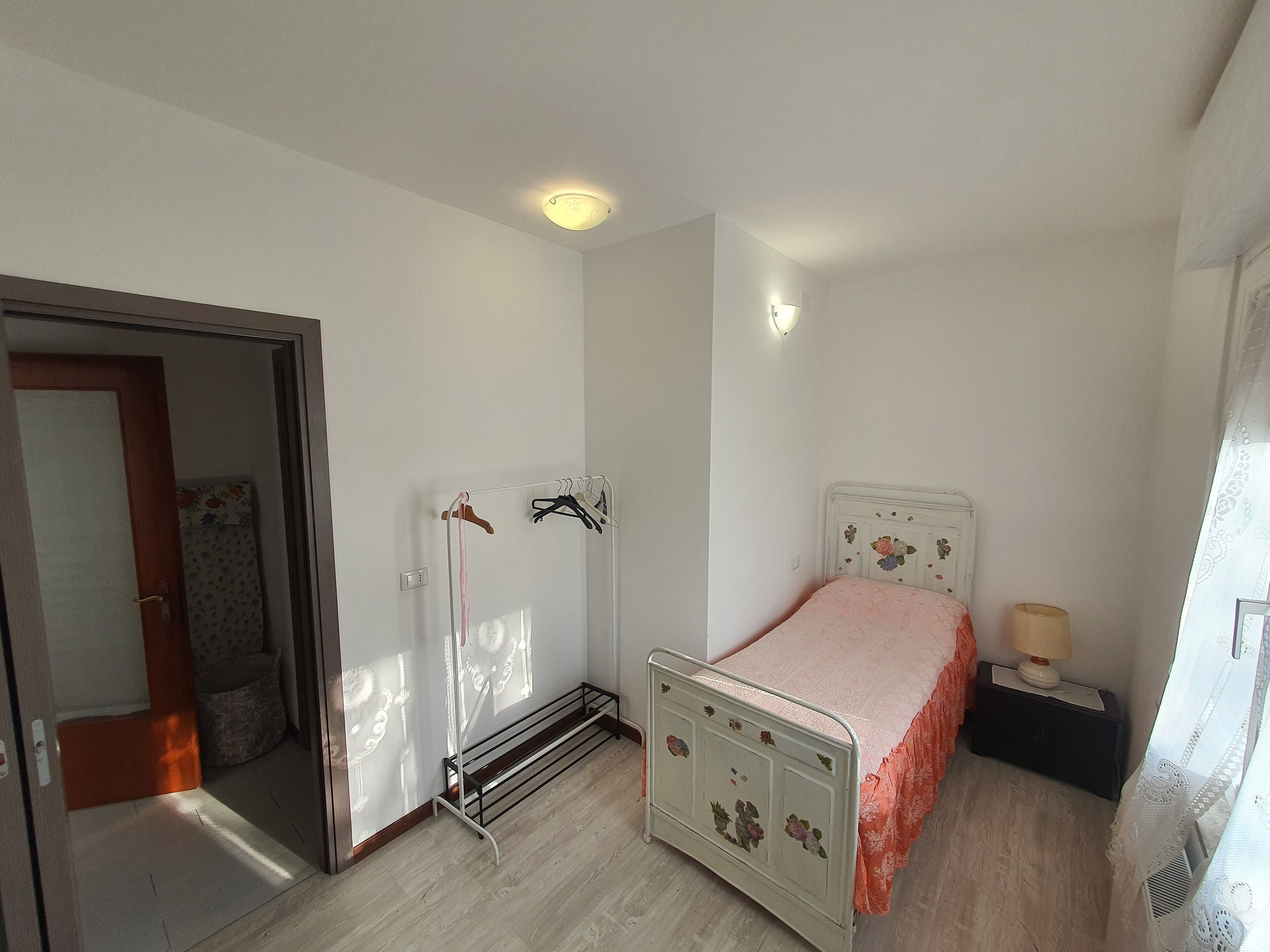Une chambre à coucher comprenant un lit, une table de chevet, une lampe, un radiateur et une armoire.