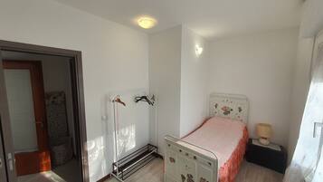Une chambre à coucher comprenant un lit, une table de chevet, une lampe, un radiateur et une armoire.