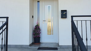 A building entrance with a white door, a mailbox, and a small Christmas tree. - A genuine stay in Friuli... (Grions)