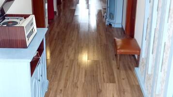A hallway with wooden flooring, a bench, a blue cabinet, and a white cabinet with a radio.
