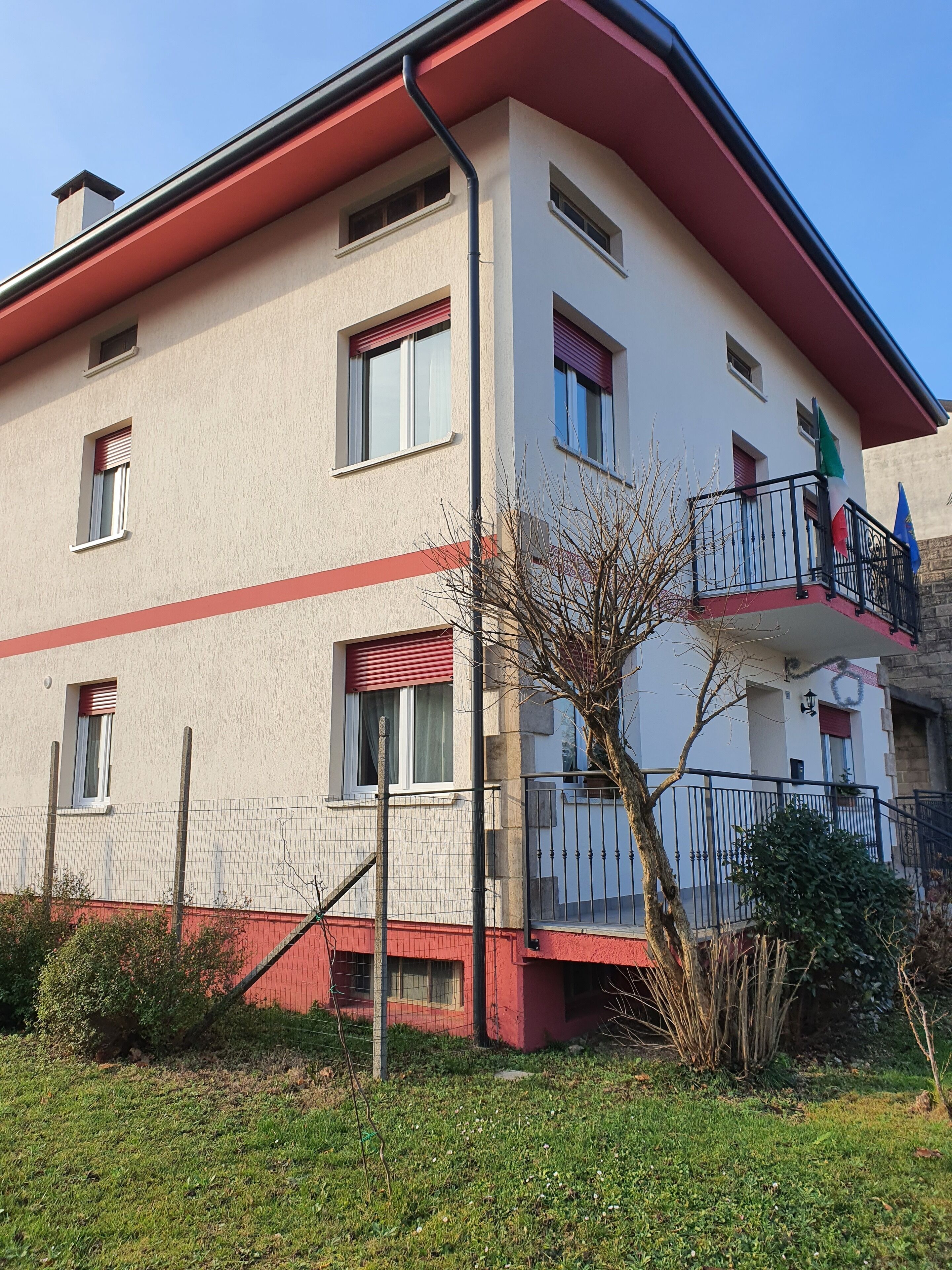 Ein mehrstöckiges Gebäude mit roter und weißer Fassade, Balkonen mit Geländern und einer Flagge.