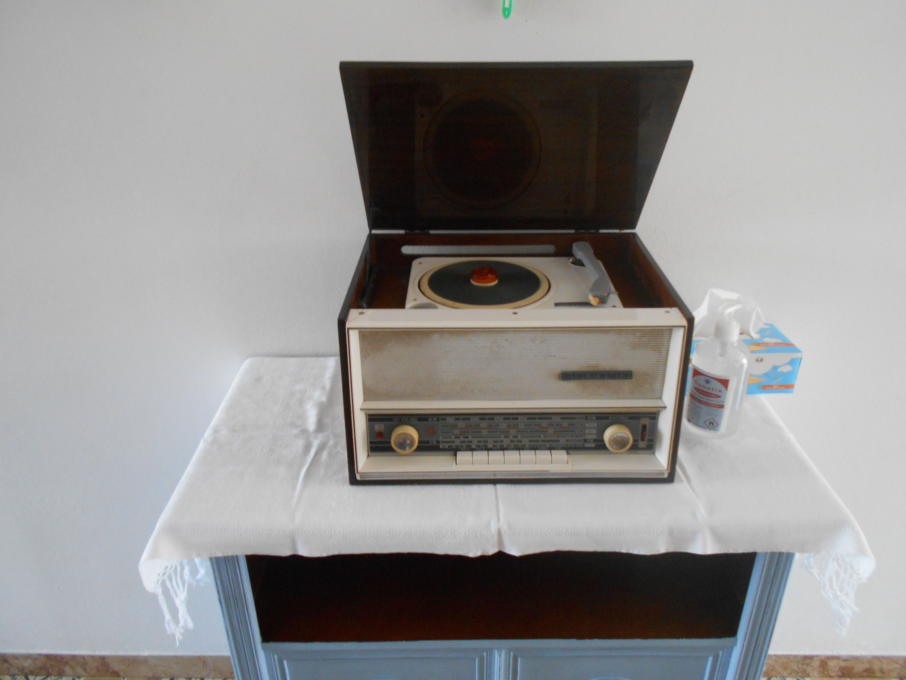 Une radio ancienne posée sur une table recouverte d’une nappe blanche.