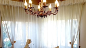 A dining area with a wooden table set for tea, surrounded by white curtains and a chandelier. - A genuine stay in Friuli... (Grions)