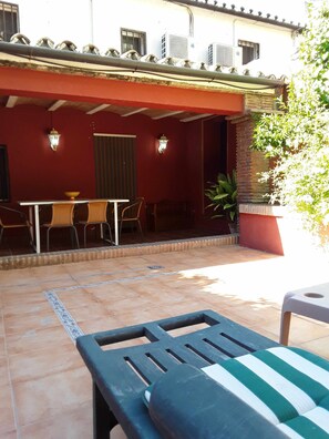 An outdoor patio area with a table and chairs, a covered seating area, and a potted plant.