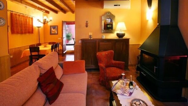 A cozy living room with a sofa, armchairs, a fireplace, and a dining area in the background. - Casas Rurales Los Arrayanes for 4 people (Ronda)