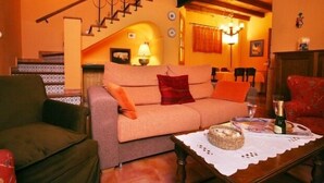 A cozy living room with a sofa, chairs, a wooden coffee table, and a staircase. - Casas Rurales Los Arrayanes for 4 people (Ronda)