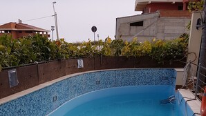 A swimming pool with a tiled edge and a wooden fence. - Apartment in villa with use Pool. Terrace, Parking (Agrigento)