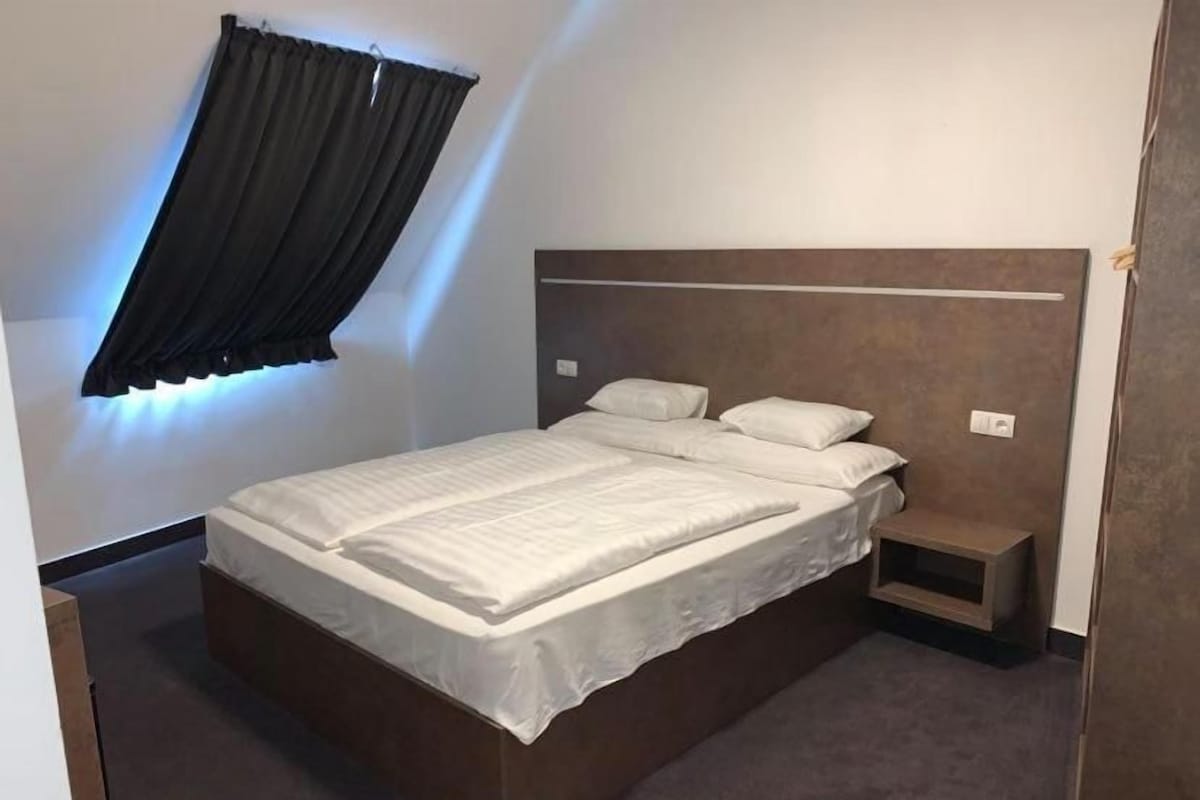 A bedroom with a bed, bedside tables, and a window with curtains.